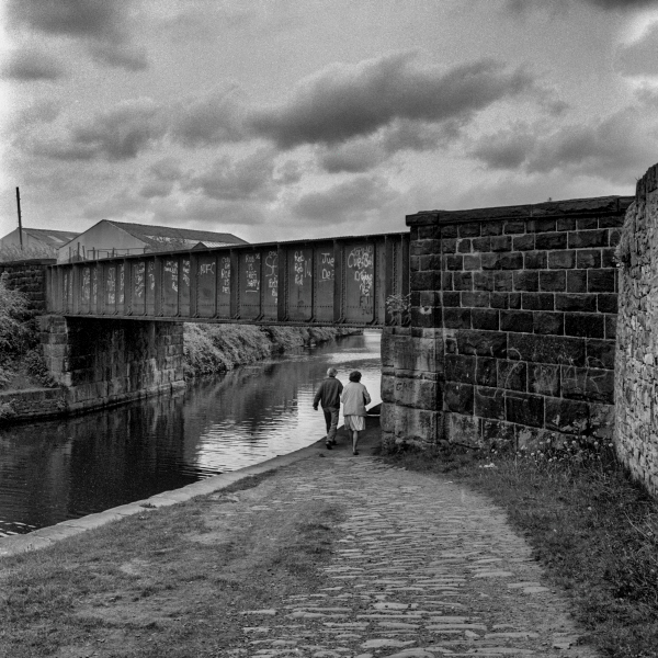 Old couple going under bridge over Leeds and Liverpool Canal, near Mill Hill, Blackburn.