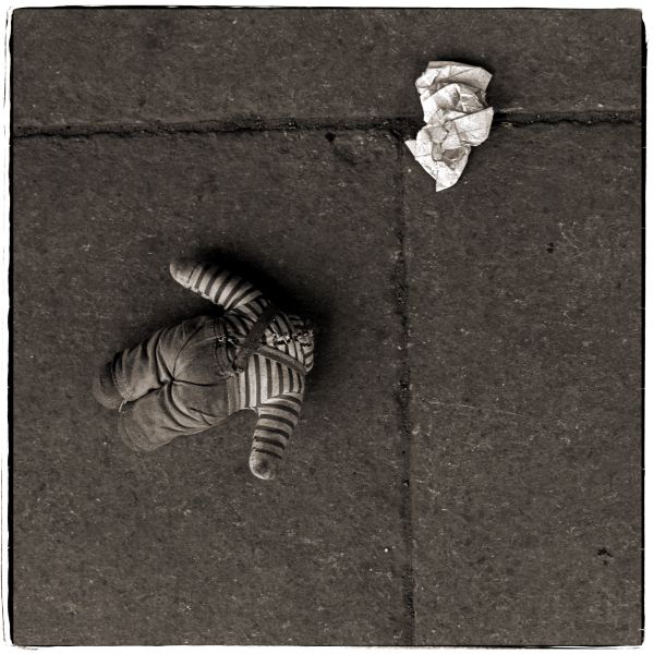 Headless soft toy and litter on pavement from Discarded a Photographic Essay by Christopher John Ball Photographer and Writer